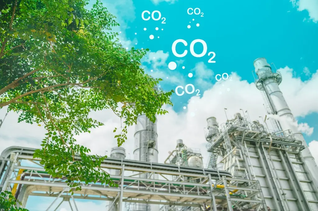 Grønt træ foran industri med CO2-udledning – træplantning som supplement, ikke erstatning for lavere udledninger
